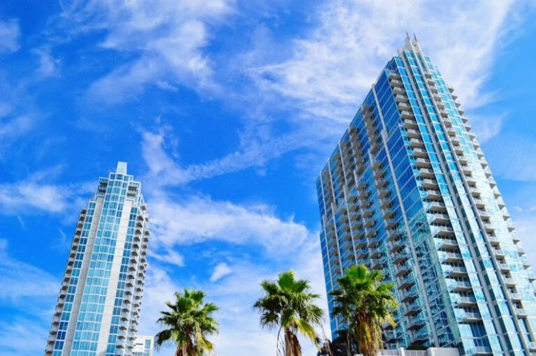 Condominium - green palm trees near high rise buildings under blue sky during daytime