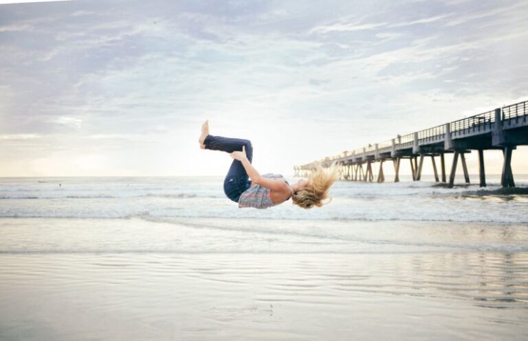 Flipping - woman doing a back flip on beachshore