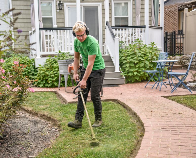 Landscaping - man in green t-shirt and black pants holding black and brown shovel