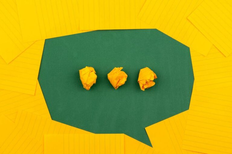 Communication - three crumpled yellow papers on green surface surrounded by yellow lined papers