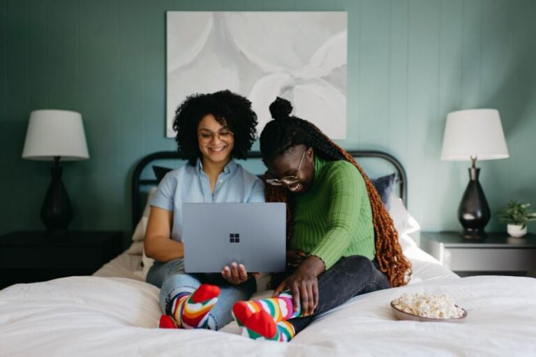 Technology - a woman sitting on a bed using a laptop