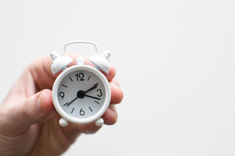 First-Time Homebuyer - person holding white mini bell alarmclock